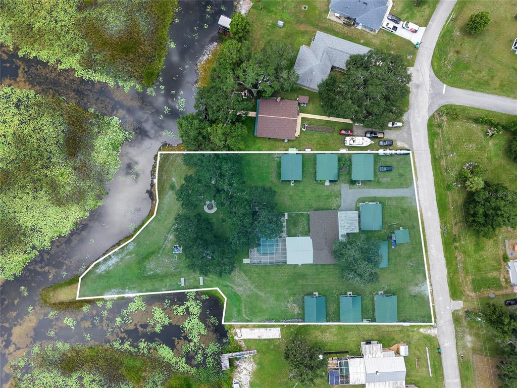 Aerial view of a waterfront property featuring a house, multiple outbuildings, and a swimming pool — 2489 N LAKEFRONT DRIVE, HERNANDO, FL