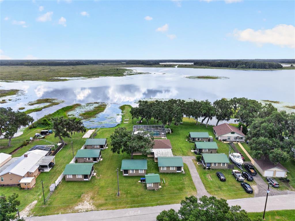 An aerial view shows several small cabins with green roofs situated near a large lake — 2489 N LAKEFRONT DRIVE, HERNANDO, FL