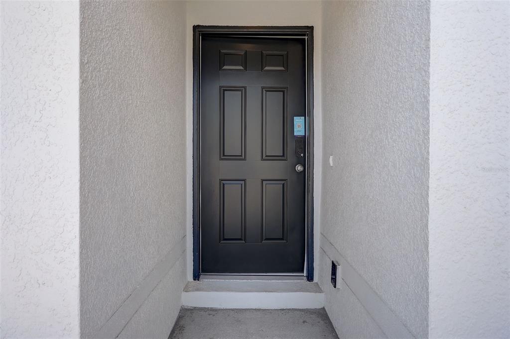 A single-story house with a white stucco exterior, a two-car garage, and a dark front door — 6755 SAN BENITO DRIVE, SEBRING, FL