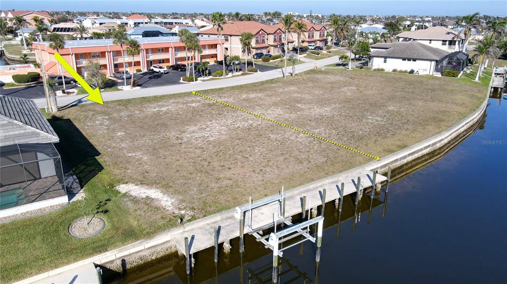 An aerial view shows a vacant waterfront lot with a boat lift and seawall — 1336 MEDITERRANEAN DRIVE, PUNTA GORDA, FL