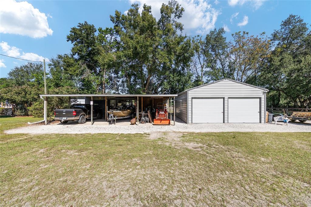 A gravel driveway leads to a metal carport and a detached two-car garage — 5985 W GULF TO LAKE HIGHWAY, CRYSTAL RIVER, FL