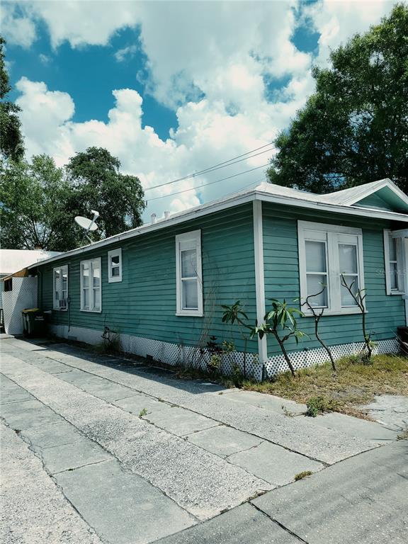 A teal, single-story house with horizontal siding and a concrete driveway sits under a cloudy sky — 1775 FRUITVILLE ROAD, SARASOTA, FL
