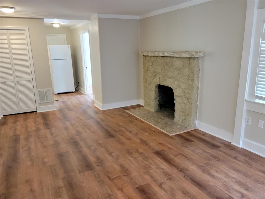 A living room features wood-look flooring, a stone fireplace, and a view into a kitchen — 1775 FRUITVILLE ROAD, SARASOTA, FL