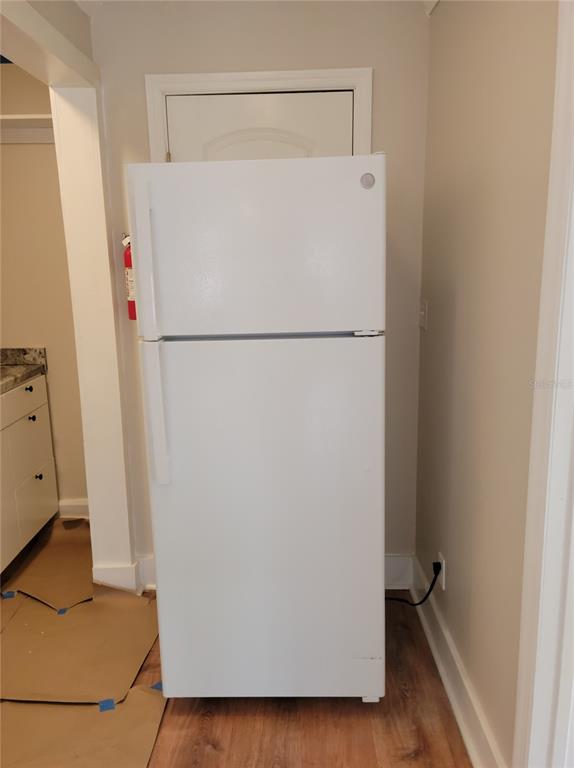 A white top-freezer refrigerator stands in a kitchen area with light-colored walls and wood flooring — 1775 FRUITVILLE ROAD, SARASOTA, FL