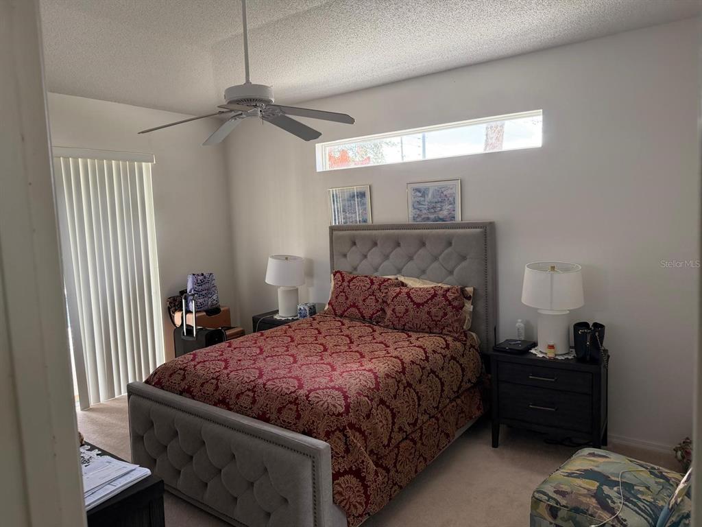 A bedroom features a tufted gray bed frame, patterned bedding, and a ceiling fan — 471 HOLBORN LOOP, DAVENPORT, FL