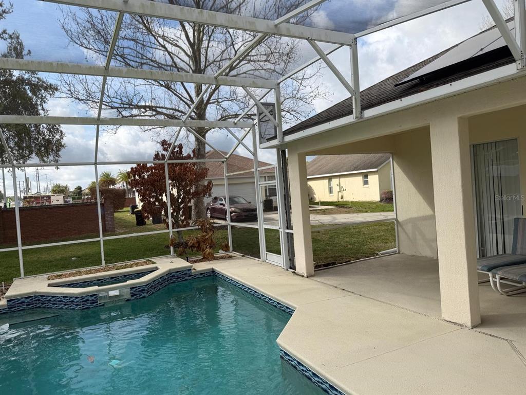 A swimming pool and spa are enclosed within a screened lanai next to a house — 471 HOLBORN LOOP, DAVENPORT, FL