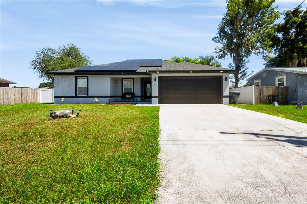 A single-story house with a gray exterior, a two-car garage, and roof-mounted solar panels — 124 PIERCE STREET, LAKE WALES, FL