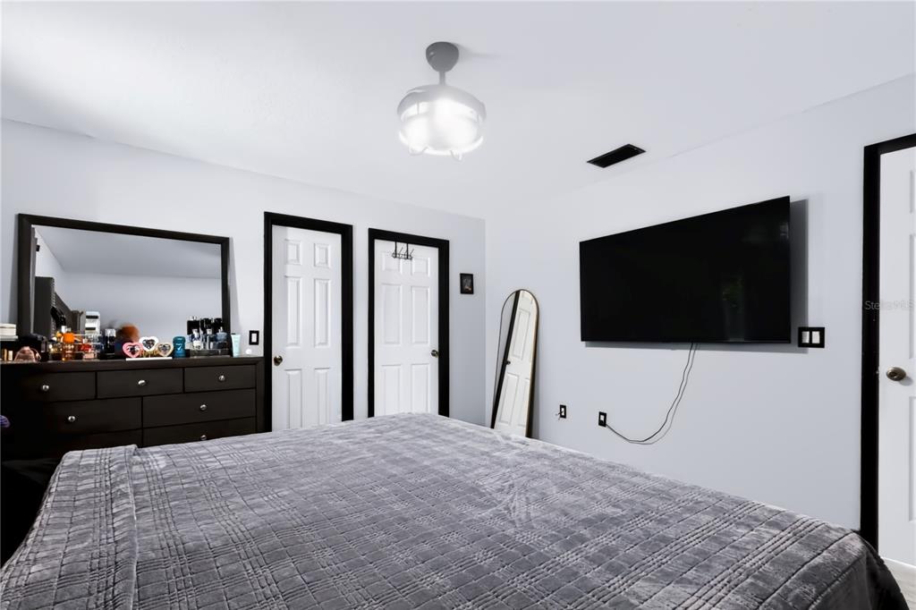 A bedroom features a bed, a dresser with a mirror, two doors, and a wall-mounted television — 124 PIERCE STREET, LAKE WALES, FL