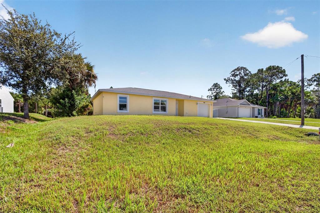A yellow single-story house with a garage sits on a grassy lot under a blue sky — 5008 S OBISPO CIRCLE, LABELLE, FL