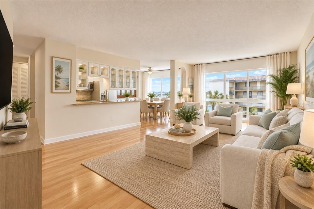 A living room with hardwood floors, a glass-topped table, and large windows overlooking a building — 660 ISLAND WAY UNIT 708, CLEARWATER BEACH, FL