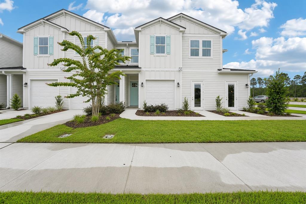 A two-story white townhouse with a garage, light blue shutters, and a front lawn — 15019 CATTERICK COURT, JACKSONVILLE, FL