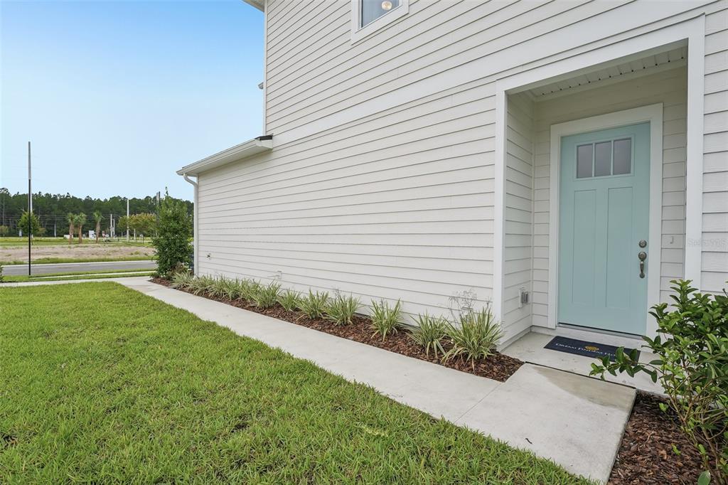 A light blue front door is set into the side of a white-sided house — 15019 CATTERICK COURT, JACKSONVILLE, FL