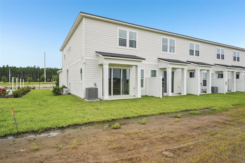 The exterior of a white multi-unit townhouse features sliding glass doors and concrete patios — 15019 CATTERICK COURT, JACKSONVILLE, FL