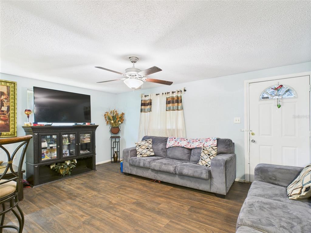 A living room features a gray sofa, a black media console, and a ceiling fan — 2119 W PATTERSON STREET, LAKELAND, FL