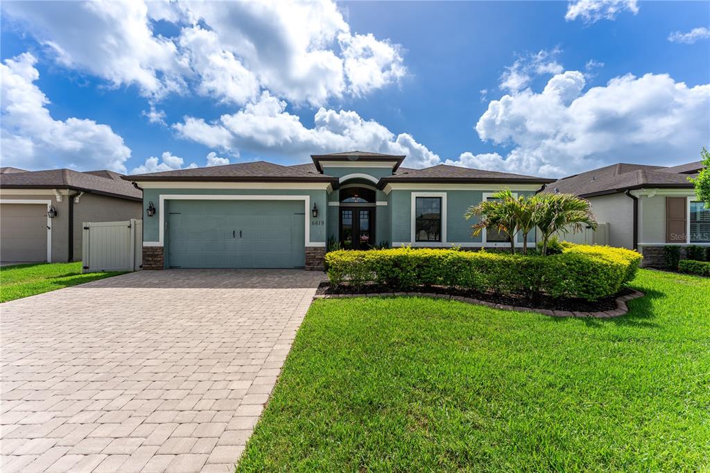 A single-story house with a teal exterior, a two-car garage, and a paved driveway — 6619 35TH COURT E, SARASOTA, FL