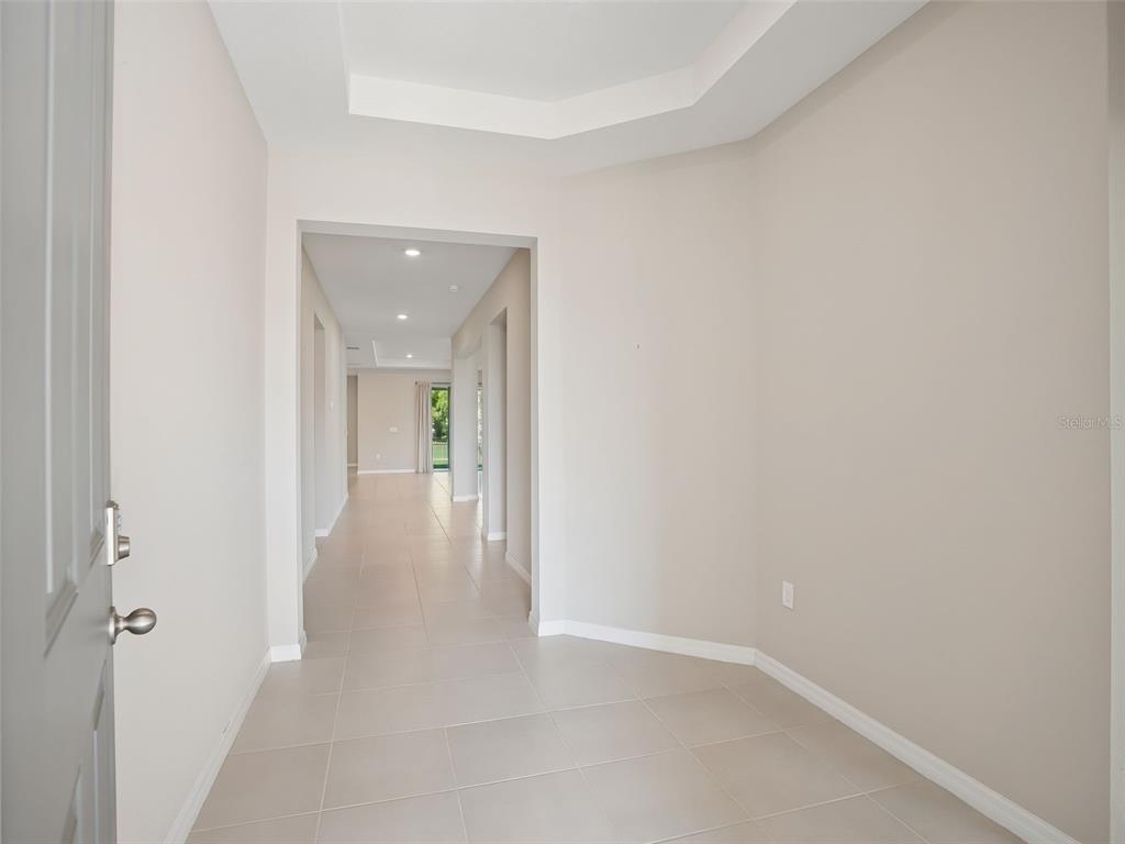A bright entryway features light-colored tile flooring, neutral walls, and a tray ceiling — 4982 NW 39TH LOOP, OCALA, FL