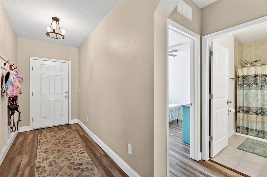 An entryway with wood-look flooring, a white front door, and doorways leading to other rooms — 2161 BRANDING IRON COURT, NEW PORT RICHEY, FL