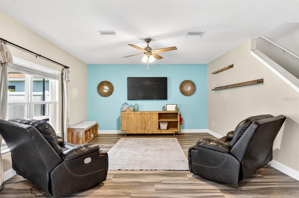 A living room features a blue accent wall, a television, and two black leather recliners — 2161 BRANDING IRON COURT, NEW PORT RICHEY, FL