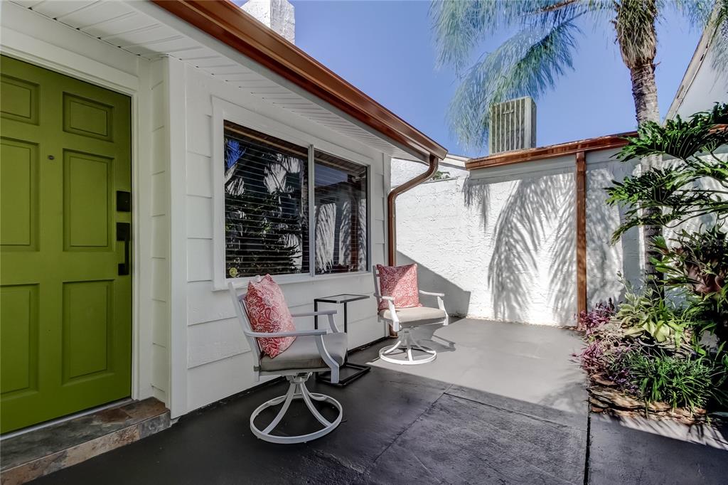 A patio with two chairs and a small table sits outside a green front door — 12625 SHELL POINT DRIVE, HUDSON, FL