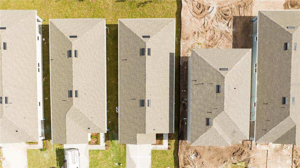 An aerial view shows several residential houses with shingled roofs and adjacent construction sites — 2847 COMMON CRANE COURT, HARMONY, FL