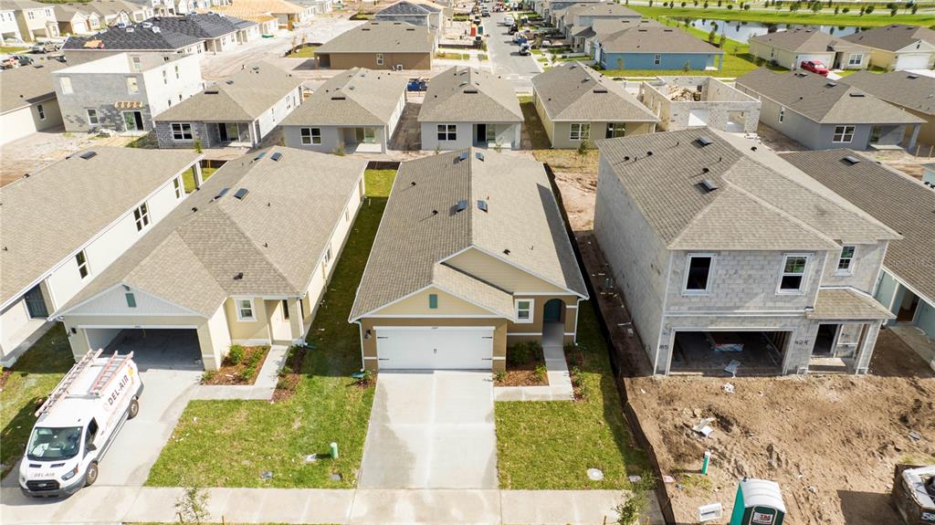 An aerial view shows three suburban houses under construction with a service van parked outside — 2847 COMMON CRANE COURT, HARMONY, FL