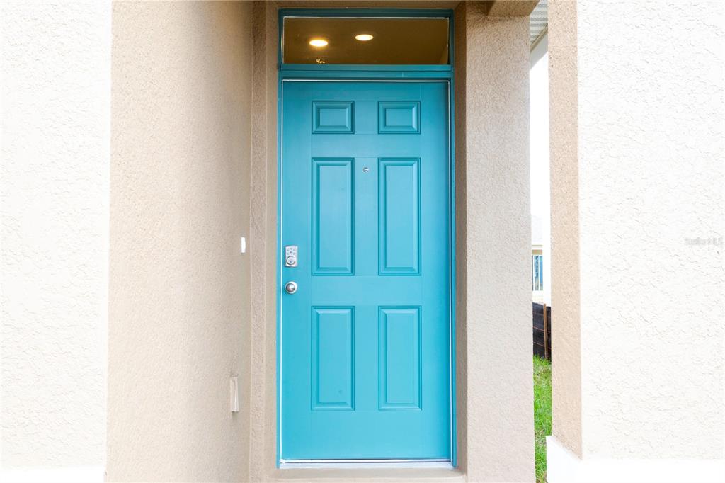A bright blue front door with a transom window is set in a stucco entryway — 2847 COMMON CRANE COURT, HARMONY, FL