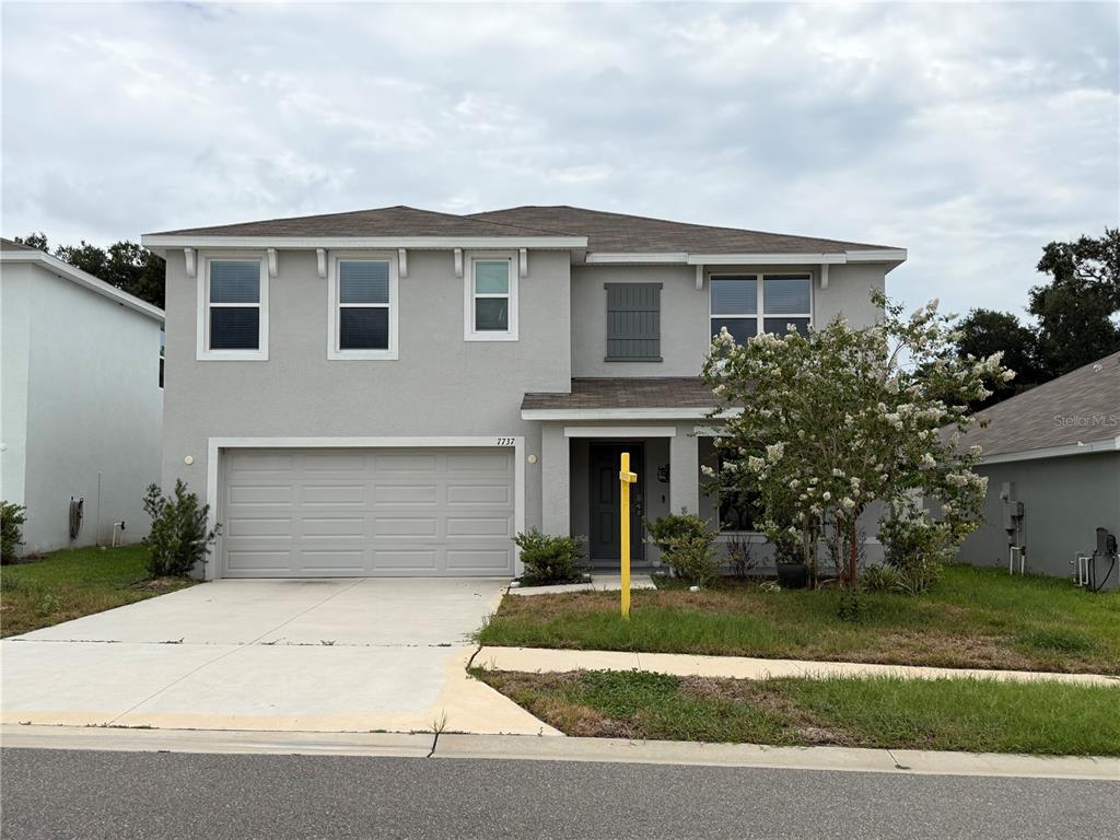 A two-story house with a gray stucco exterior, a two-car garage, and a front yard — 7737 ROSEWOOD GARDEN LOOP, TAMPA, FL