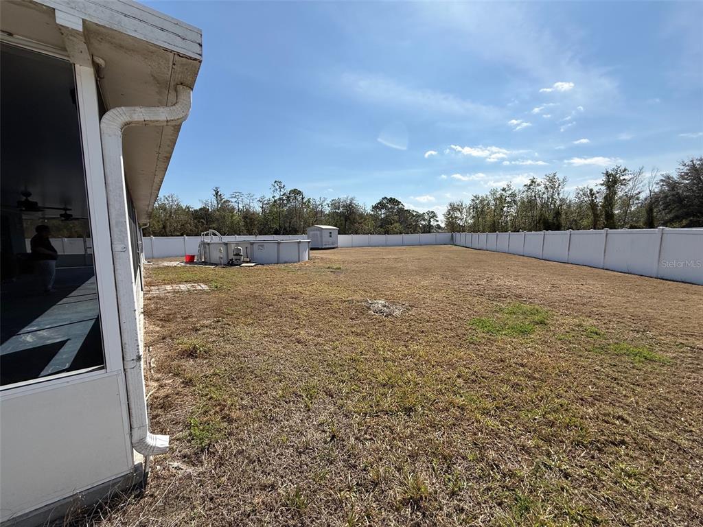 A large, fenced backyard features a small above-ground pool and a storage shed — 710 BLUEBILL PLACE, KISSIMMEE, FL