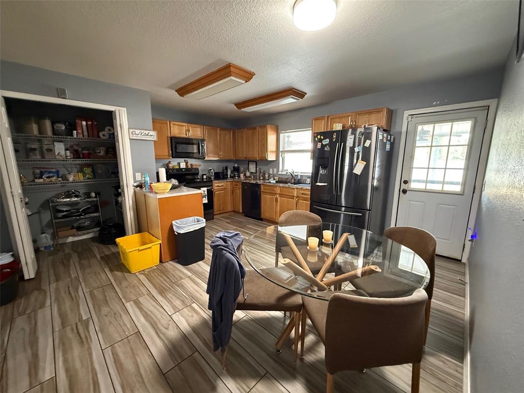 A kitchen features wood cabinets, stainless steel appliances, a glass dining table, and tile flooring — 710 BLUEBILL PLACE, KISSIMMEE, FL