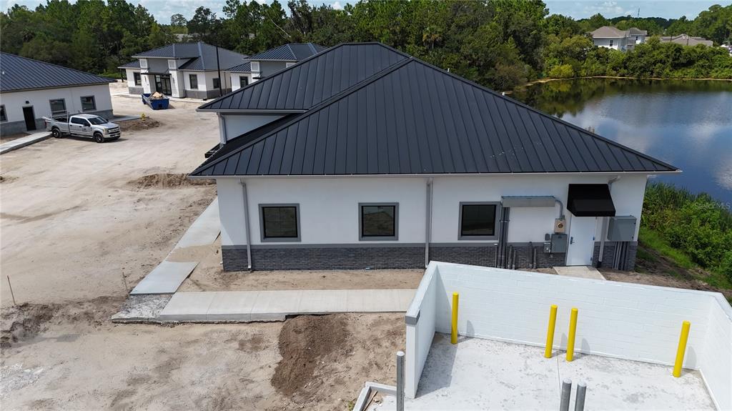 An aerial view shows two commercial buildings under construction with metal roofs and scaffolding — 30 EXCHANGE LOOP LOOP UNIT 7, PALM COAST, FL