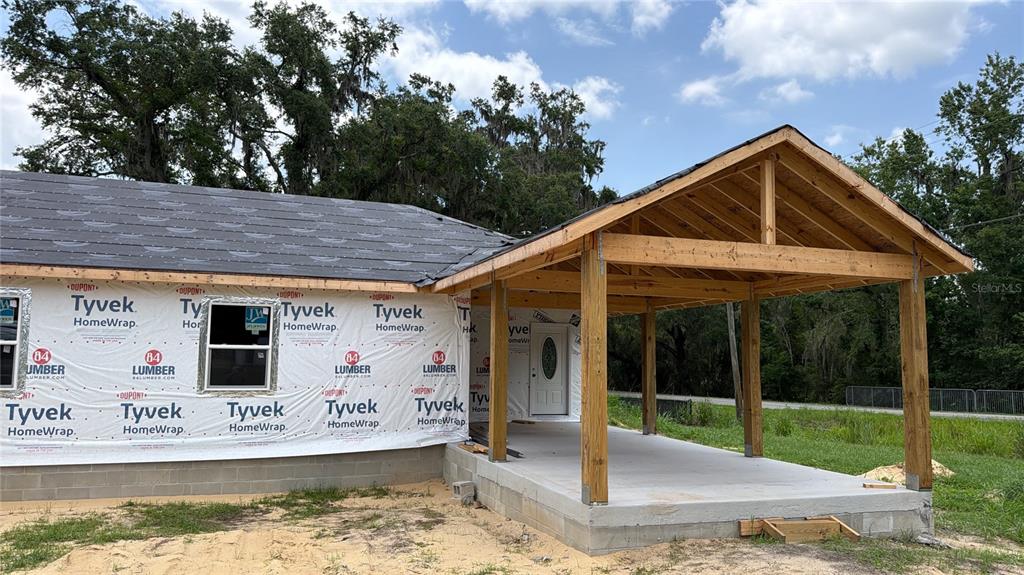 An exterior view of a house under construction featuring a covered porch and Tyvek wrap — 2305 TIMBERCREEK LOOP E, LAKELAND, FL
