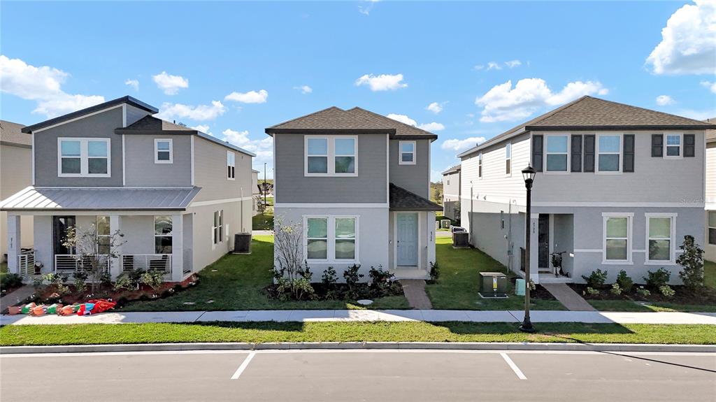 Three two-story suburban houses with gray siding stand side-by-side along a paved street — 4704 HOMESTEAD TRAIL, ST CLOUD, FL