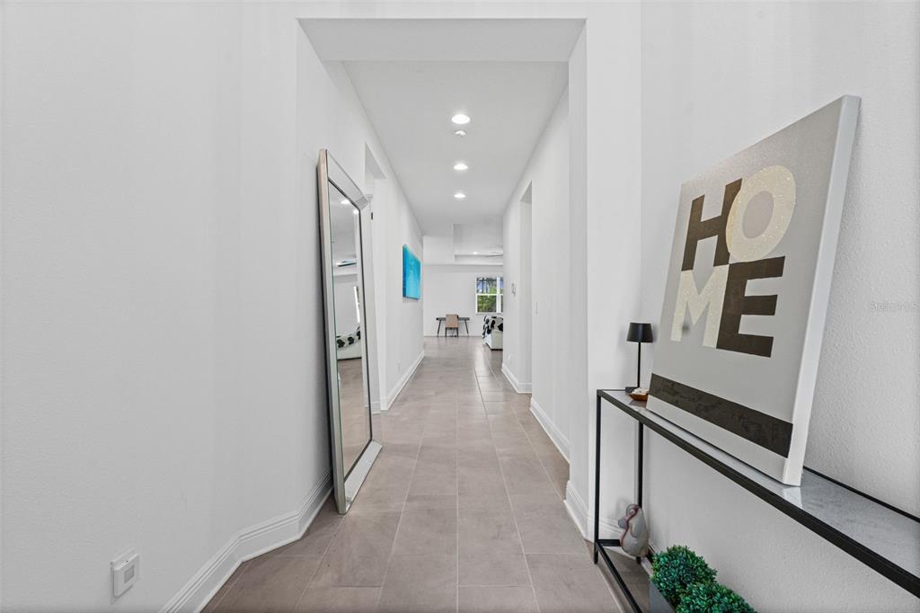 A bright hallway features light tile flooring, a floor mirror, and a console table — 1024 FERNLEAF RUN, BRADENTON, FL