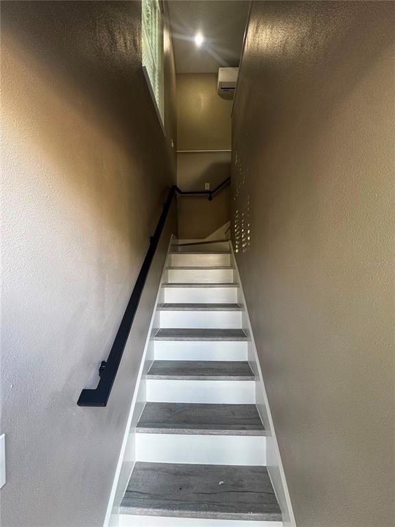 A narrow staircase with wood-look treads and white risers leads to an upper landing — 327 AVENUE J SE, WINTER HAVEN, FL