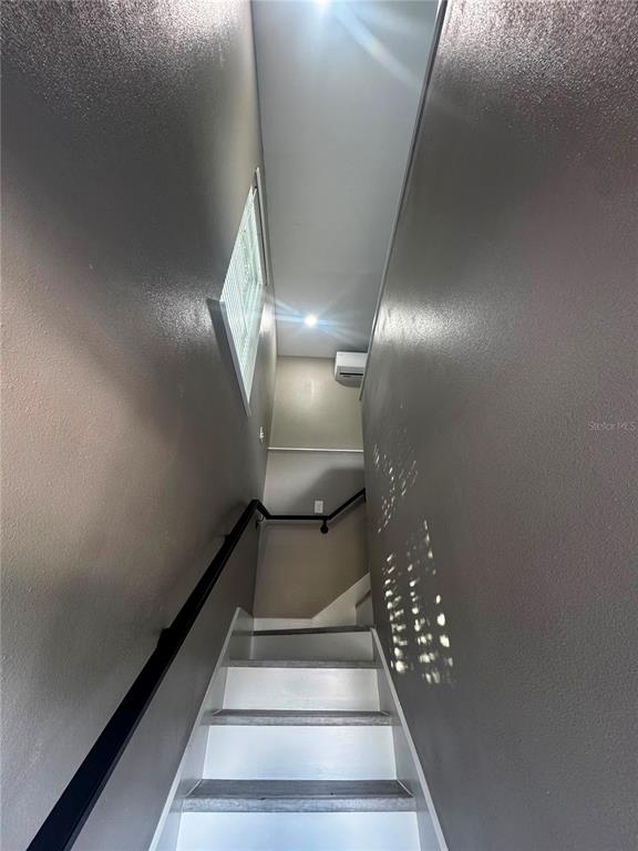 A narrow staircase with white treads and dark gray walls leads to an upper landing — 327 AVENUE J SE, WINTER HAVEN, FL