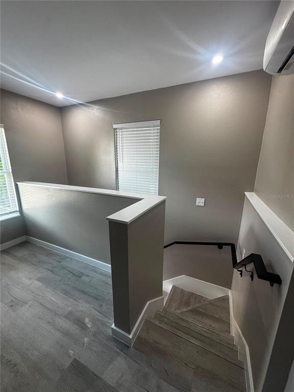 A staircase with a black handrail leads down from a landing with gray wood flooring — 327 AVENUE J SE, WINTER HAVEN, FL