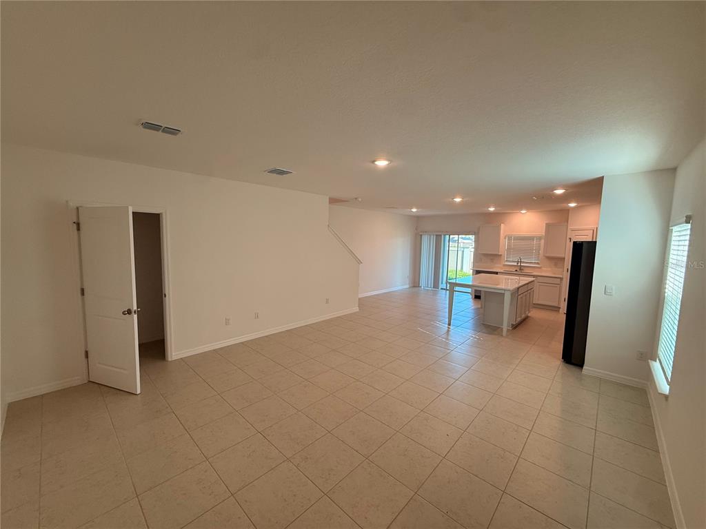 An open-concept living area features tile flooring, a kitchen island, and a white door — 10771 IRONWOOD TREE WAY, SAN ANTONIO, FL