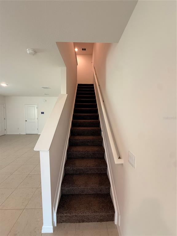 A carpeted staircase with a white railing leads to an upper level in a room — 10771 IRONWOOD TREE WAY, SAN ANTONIO, FL