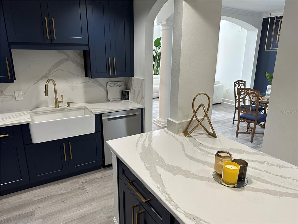 A kitchen features navy blue cabinets, white marble-patterned countertops, and a farmhouse sink — 808 3RD AVENUE W UNIT 701, BRADENTON, FL