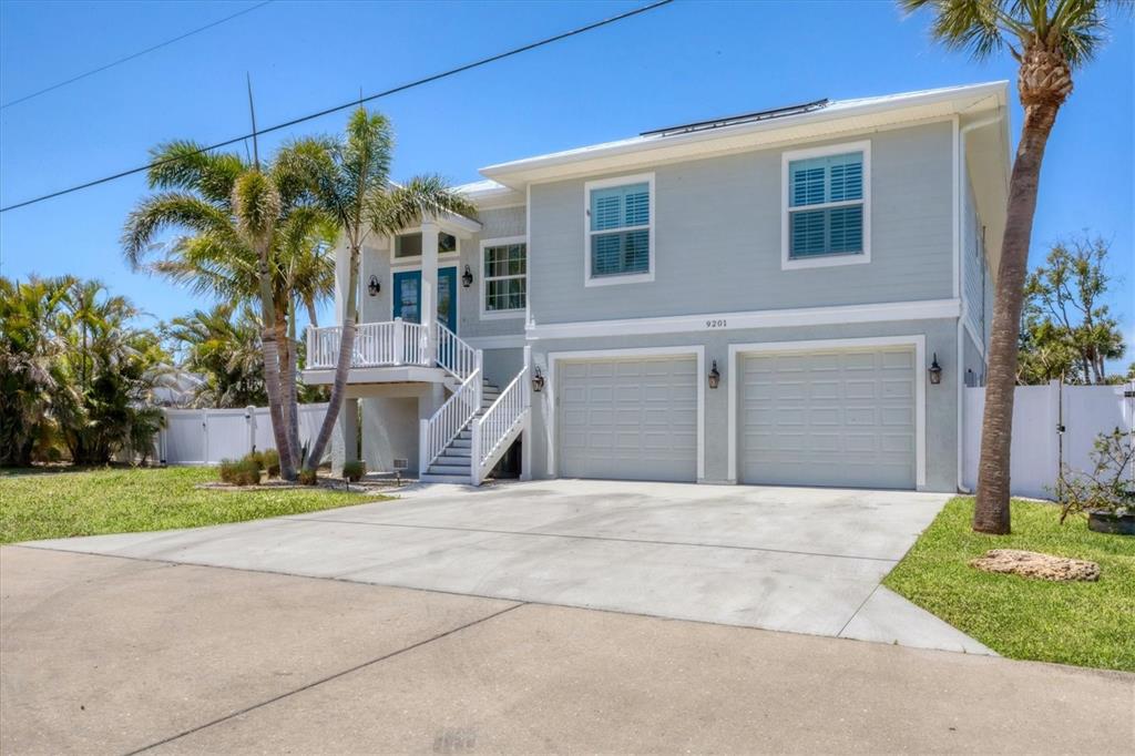 A two-story house with light blue siding, a two-car garage, and an elevated front entrance — 9201 LAKE DRIVE, ENGLEWOOD, FL