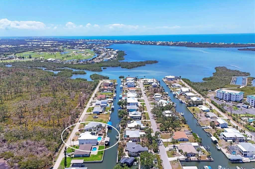 An aerial view shows a waterfront house with a pool in a canal-side neighborhood — 9201 LAKE DRIVE, ENGLEWOOD, FL