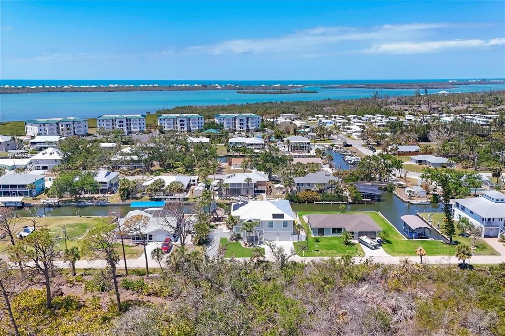 An aerial view shows waterfront homes, canals, and multi-story buildings near the ocean — 9201 LAKE DRIVE, ENGLEWOOD, FL