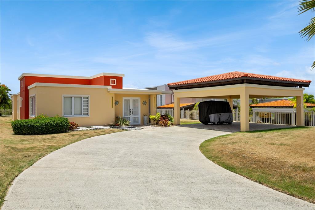 A single-story house with a beige exterior, a covered carport, and a paved driveway — 106 MORNING DEW G-14, SUNRISE AT PALMAS DEL MAR, HUMACAO, PR