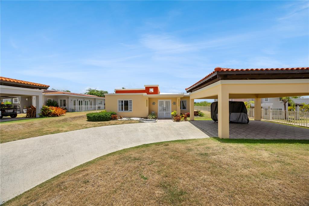 A single-story house with a concrete driveway, a covered carport, and a palm tree — 106 MORNING DEW G-14, SUNRISE AT PALMAS DEL MAR, HUMACAO, PR