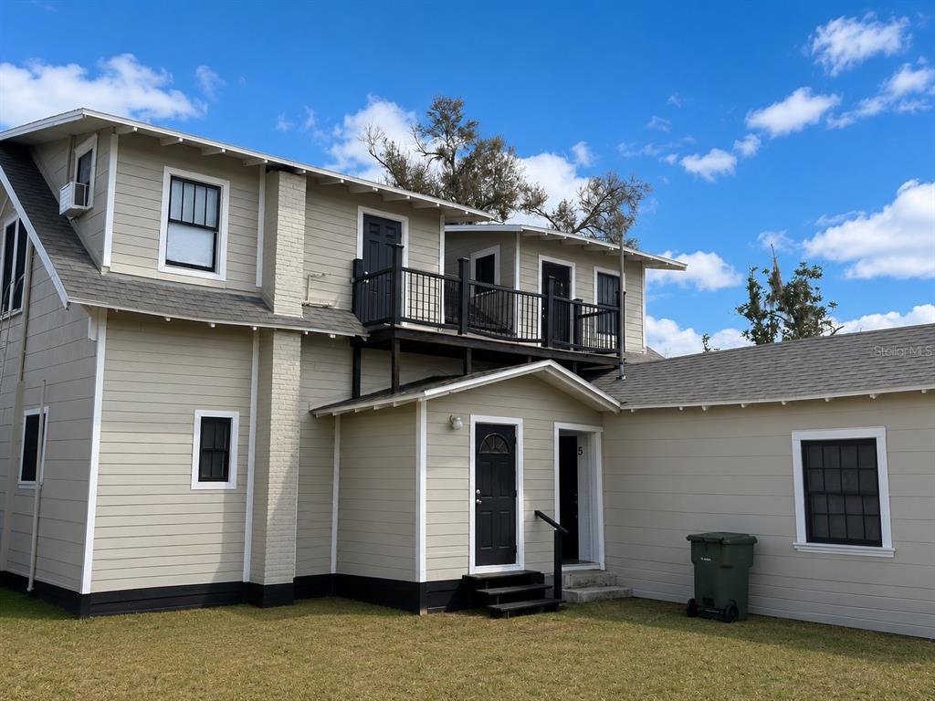 A two-story light-colored building with black railings and stairs sits on a grassy lot — 1339 7TH STREET SW, WINTER HAVEN, FL
