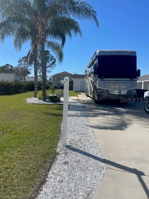 A large recreational vehicle is parked on a grassy lot with palm trees — 1064 CARAVAN LOOP, POLK CITY, FL
