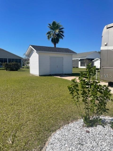 An RV is parked next to a white storage shed on a grassy lot — 1064 CARAVAN LOOP, POLK CITY, FL