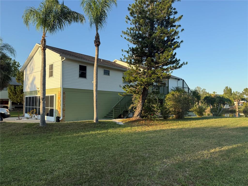 A two-story house with light siding and green lower walls stands near a large tree — 3338 FERNLEAF DRIVE, HERNANDO BEACH, FL