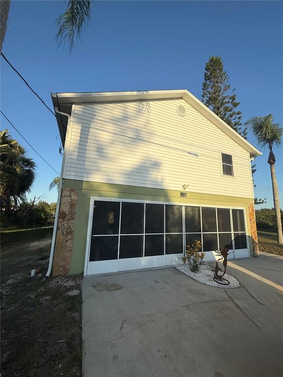 The exterior of a two-story house features white siding, a screened-in garage, and stone accents — 3338 FERNLEAF DRIVE, HERNANDO BEACH, FL