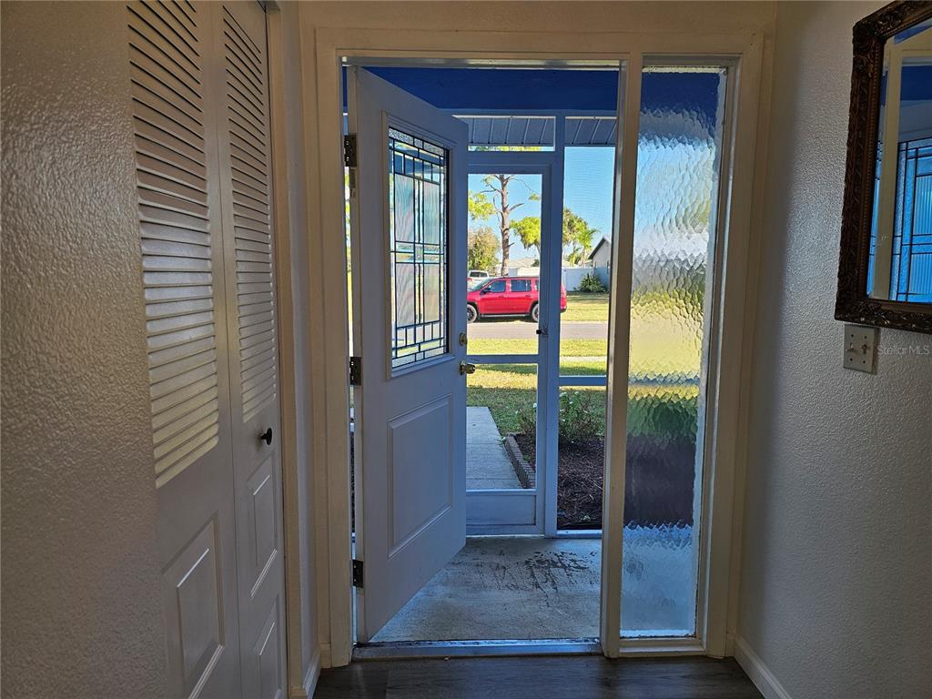 An open front door reveals a screen door and a view of a residential street — 5437 TALBROOK ROAD, NORTH PORT, FL